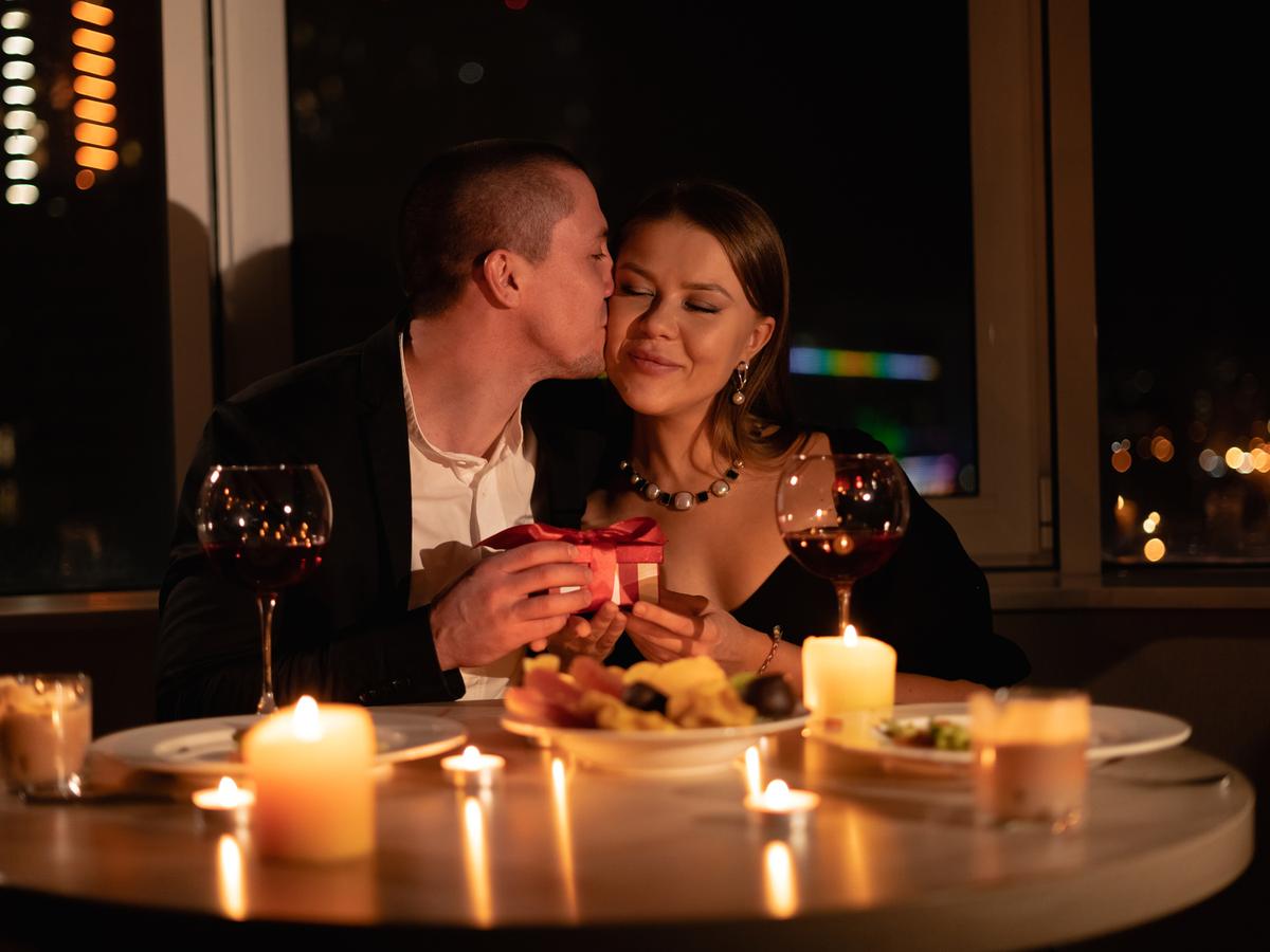 Ein Paar beim Abendessen zu Hause, der Tisch voller Kerzen.